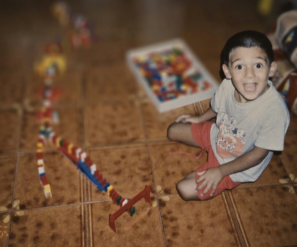 Tiziano Trazzi as a child, building a domino run across the floor tiles